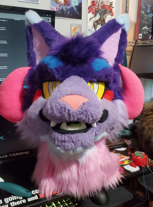 The head of Bleeding Heart, a brightly colored cat beast with curled pink horns.