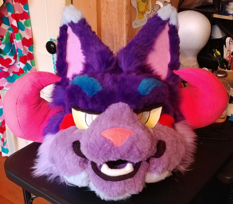 The head of Bleeding Heart, a brightly colored cat beast with curled pink horns.