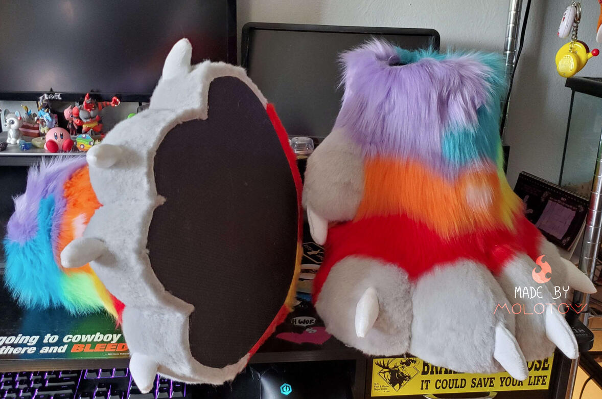 The rainbow colored feet paws of Quartz. The foot on the left of the image is turned on its side, showing the foam padding on the bottom.